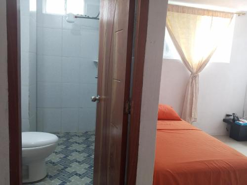 a bathroom with a bed and a toilet in a room at Pelican Tours in Puerto Baquerizo Moreno