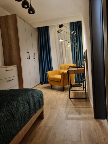 een slaapkamer met een bed en een gele stoel bij Apartament Loft KB-Ściegiennego (garaż, centrum) in Kielce