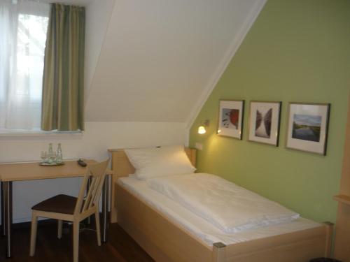 Habitación pequeña con cama y escritorio. en Stadthotel Bocholt, en Bocholt