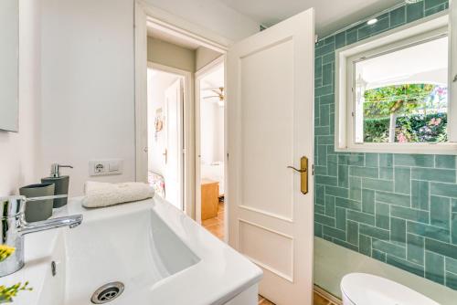 uma casa de banho com um lavatório branco e uma parede de azulejos verdes em Las Violetas em Arenal d'en Castell