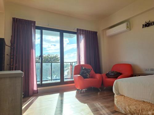 een slaapkamer met 2 stoelen en een bed en een groot raam bij 上圓旅店 到沙灘,7-11只要3分鐘 in Nanwan