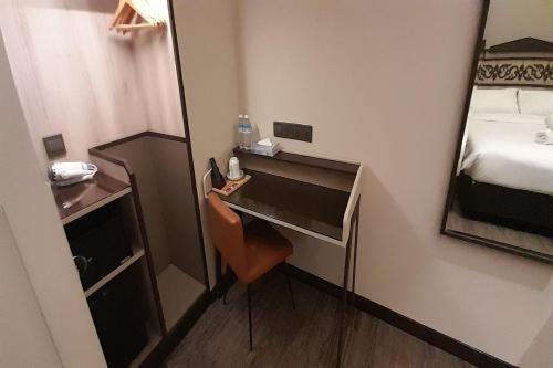 a small room with a desk and a mirror at Lion Peak Hotel Hamilton in Singapore