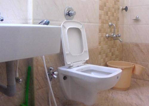 a bathroom with a toilet with the lid up at Chetinaad Courtyard Gandhipuram by Centre Park in Coimbatore