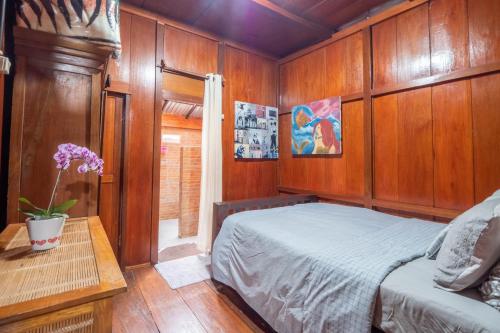 een slaapkamer met houten wanden en een bed en een tafel bij rumah kayu sulawesi antique in Bedugul