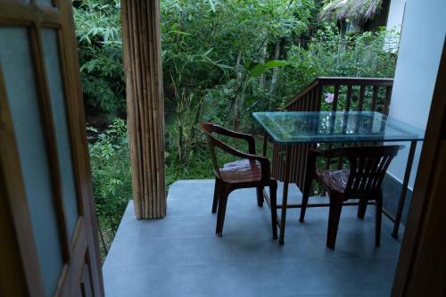 a glass table and two chairs on a balcony at Balishira Resort Ltd. in Sreemangal