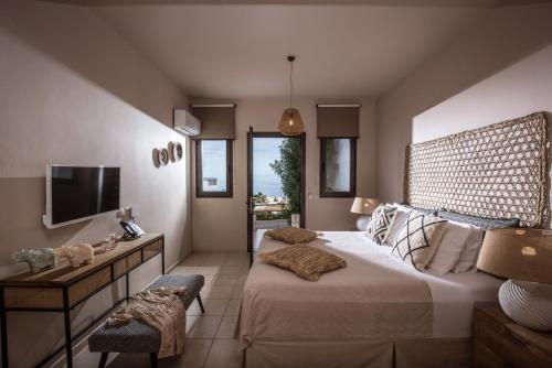 Creta Blue Boutique Hotel في خيرسونيسوس: غرفة نوم بسرير كبير وتلفزيون