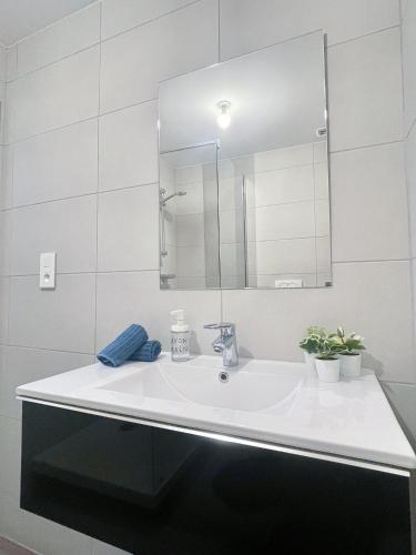 une salle de bain blanche avec un lavabo et un miroir dans l'établissement Le BarberShop, centre ville, parking gratuit, à Mulhouse