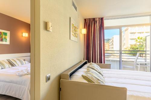 トッサ・デ・マールにあるMedplaya Aparthotel Esmeraldasのベッド2台とバルコニーが備わるホテルルームです。
