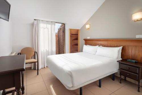 Hotel Victoria Valdemoro في فالديمورو: غرفة نوم مع سرير أبيض كبير ومكتب