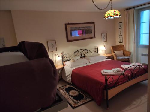 a bedroom with a bed with a red blanket and a chair at Hotel Soazza in Soazza