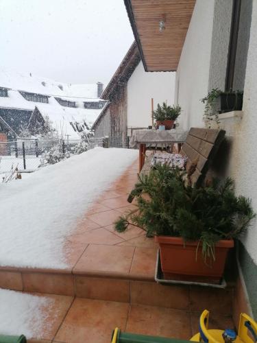 a patio with a table and benches in the snow at Apartma Tilika in Kranjska Gora