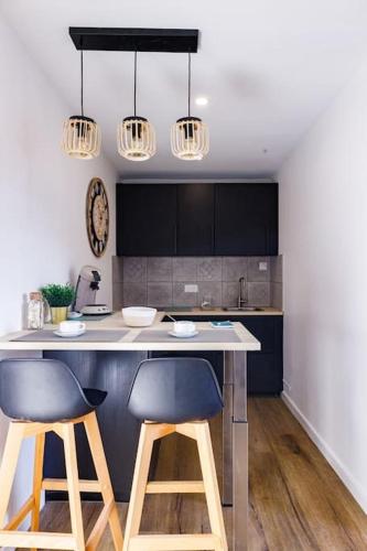 une cuisine avec deux tabourets de bar à un comptoir dans l'établissement Joli appartement, Le Bouchon Rémois, centre ville, à Reims