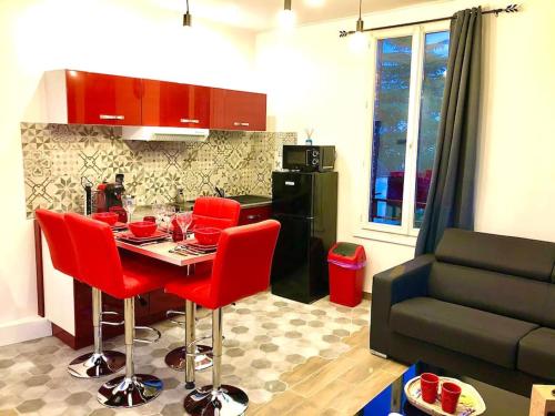 eine Küche mit einem Tisch, roten Stühlen und einem Sofa in der Unterkunft Le Led Room,Centre ville place de parking gratuite in Sens