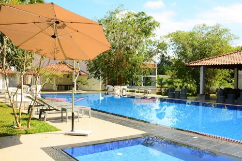 an umbrella next to a swimming pool with a resort at The Covanro Airport Hotel - Katunayake in Gampaha