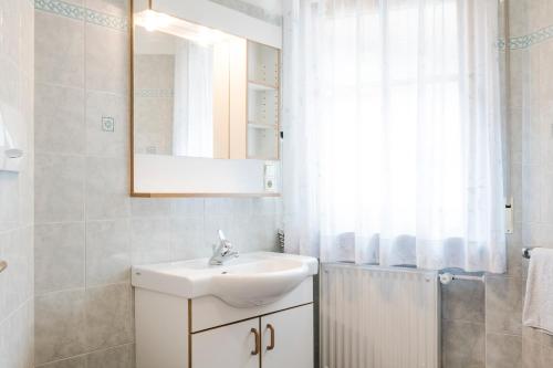 a white bathroom with a sink and a mirror at Residence Am Wegkreuz in Senales