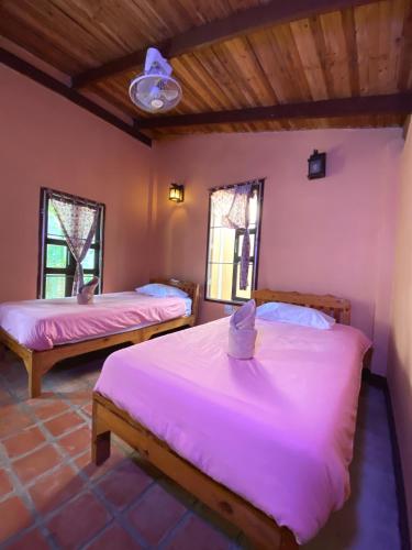 a bedroom with two beds and two windows at Mountainblues in Kampong Huaibū