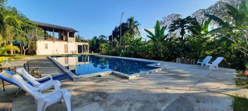 a swimming pool with two white chairs next to a house at Mountainblues in Kampong Huaibū