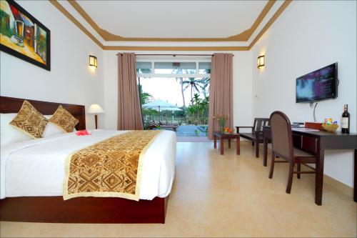 Habitación de hotel con cama, escritorio y TV. en Green Areca villa, en Hoi An