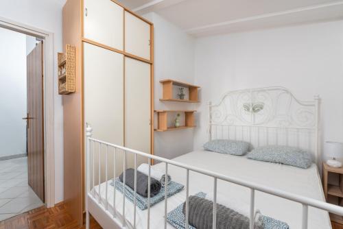 Un pequeño dormitorio con una cama blanca y una escalera en Apartman Tea, en Novigrad Istria