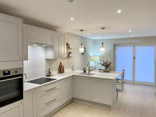 a kitchen with white cabinets and a large window at Modern, central bungalow with Luxury Hot tub in Bournemouth