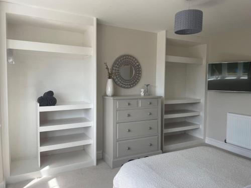 a bedroom with white shelves and a dresser at Modern, central bungalow with Luxury Hot tub in Bournemouth