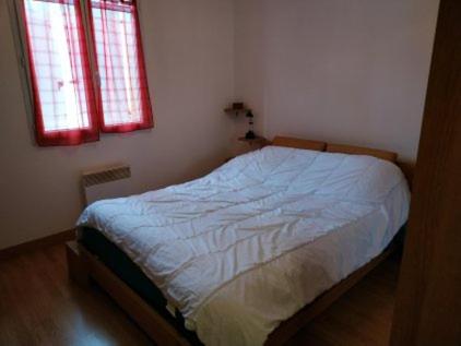 a bed in a bedroom with two windows at Pavillon 6 personnes in Corgirnon