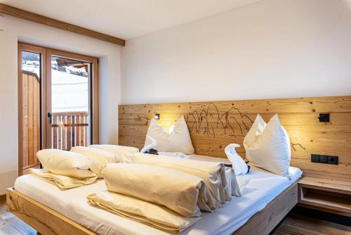 a bedroom with three beds with white pillows at Planerhof Apartment Alpenrose in Funes