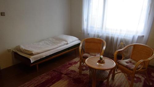 a small room with a bed and two chairs and a table at Apartmán 6 km od centra Banskej Bystrice in Banská Bystrica