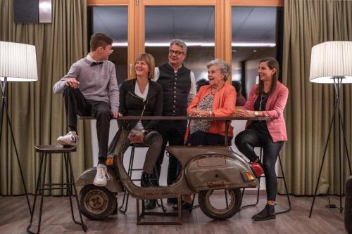a group of people sitting around a table with a scooter at Hotel Condor in San Vigilio Di Marebbe