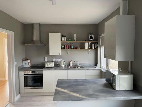 a kitchen with white cabinets and a stove top oven at Donegal Beach Cottage with Sea Views, sleeps six in Lettermacaward