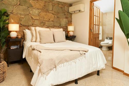 1 dormitorio con 1 cama grande y pared de piedra en AmazINN Places private Splash Pool and relaxing Sound of Sea en Panamá