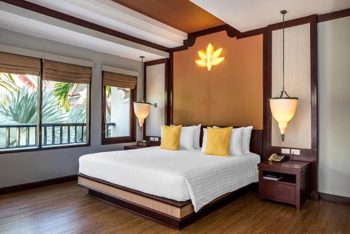 - une chambre avec un grand lit blanc et des oreillers jaunes dans l'établissement Beyond Samui, à Chaweng