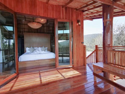 Schlafzimmer mit einem Bett auf einer Holzterrasse in der Unterkunft Pan's farm แบ่งปันฟาร์ม in Ban San Phaya Loei Luang