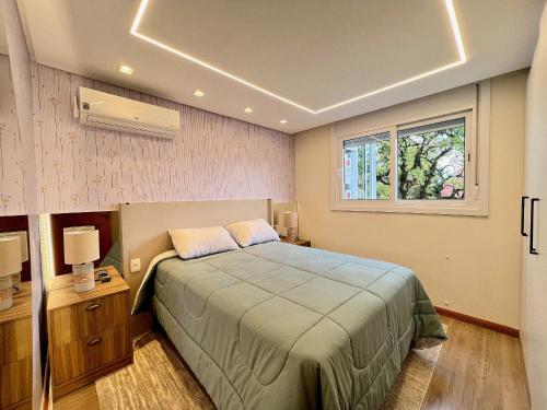 a bedroom with a bed and a window at Apartamento Solar do Ipê Centro 2 dorm by Achei in Canela