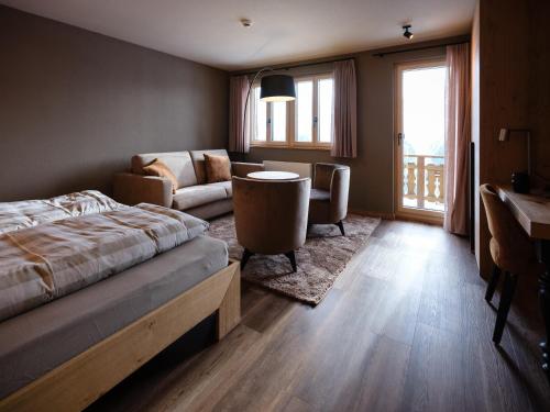 um quarto com uma cama, um sofá e uma mesa em Panorama Hotel & Restaurant em Bettmeralp