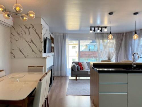 eine Küche und ein Wohnzimmer mit einem Tisch und einer Couch in der Unterkunft Apartamentos Solar da Garibaldi CENTRO by Achei Gramado in Gramado