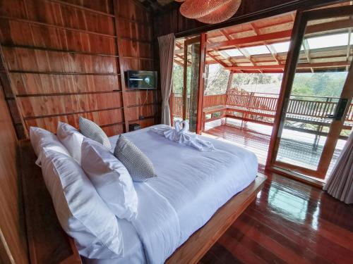 a bed in a wooden room with a large window at Pan's farm แบ่งปันฟาร์ม in Ban San Phaya Loei Luang