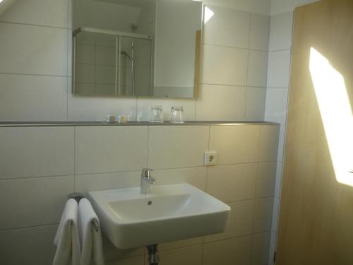 a bathroom with a sink and a mirror and towels at Stadthotel Bocholt in Bocholt
