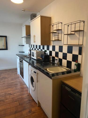 a kitchen with a sink and a washing machine at Nantwich House in Crewe