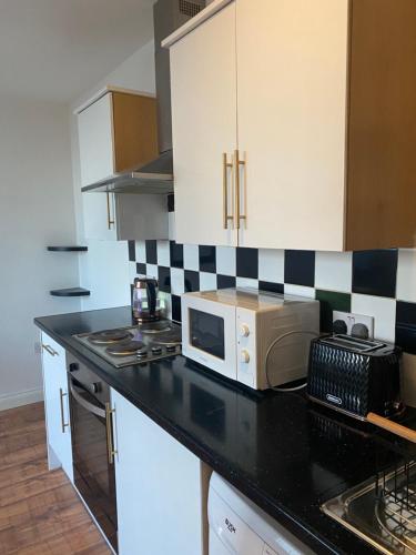 a kitchen with a black counter top with a microwave at Nantwich House in Crewe