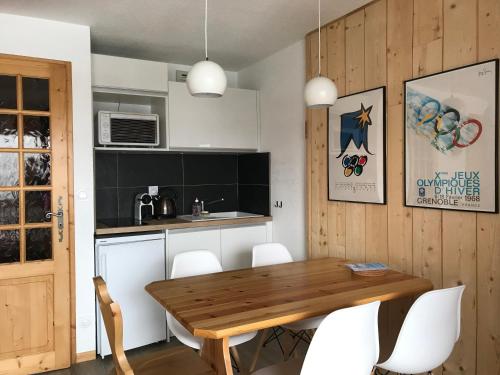 cocina con mesa de madera y sillas blancas en Appartement 1 chambre, 4 personnes, en Champagny-en-Vanoise