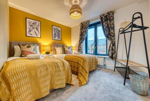 two beds in a room with yellow walls at Ashcroft Loft by Apricity Property - Stunning 3 Bedroom, 2 bathrooms, Cosy Central Apartment with balcony in Cirencester