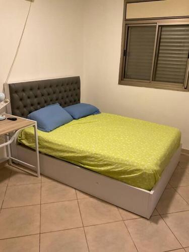 łóżko z żółtym kocem i niebieskimi poduszkami w obiekcie באר אשקלון w mieście Aszkelon
