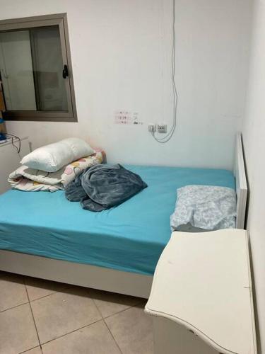 een klein bed met blauwe lakens en kussens in een kamer bij באר אשקלון in Ashkelon