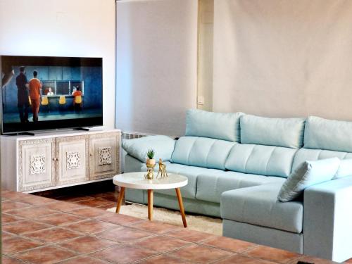 sala de estar con sofá azul y mesa en Casa Rural El Canto Del Agua, en Malpartida de Plasencia