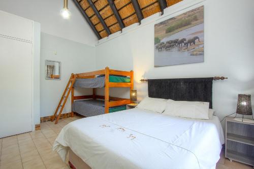 a bedroom with a bed and a painting on the wall at NJIRI LODGE - Your part of Africa in Marloth Park