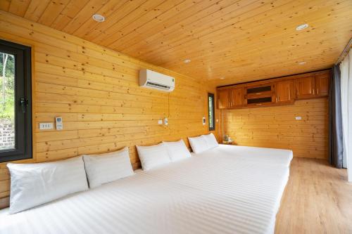 a bedroom with a white bed in a wooden wall at Les Bois BaVi by HOLO Serviced HomeStay in Hanoi