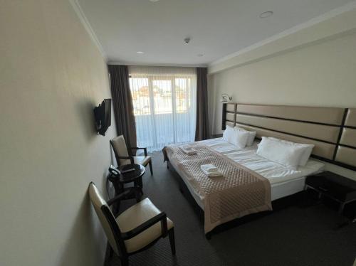 a hotel room with a bed and two chairs at Hotel Genio in Tbilisi City