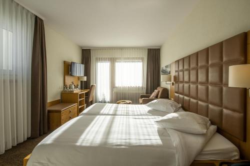 Cette chambre comprend un grand lit et une chaise. dans l'établissement Hotel Olympic - Montana Center, à Crans-Montana