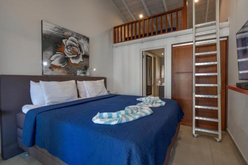 a bedroom with a bed with a blue blanket and a ladder at Boutique Hotel Swiss Paradise Aruba Villas and Suites in Palm-Eagle Beach